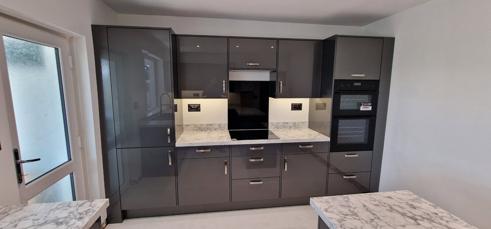 Completed grey gloss kitchen with integrated appliances and under-unit lighting